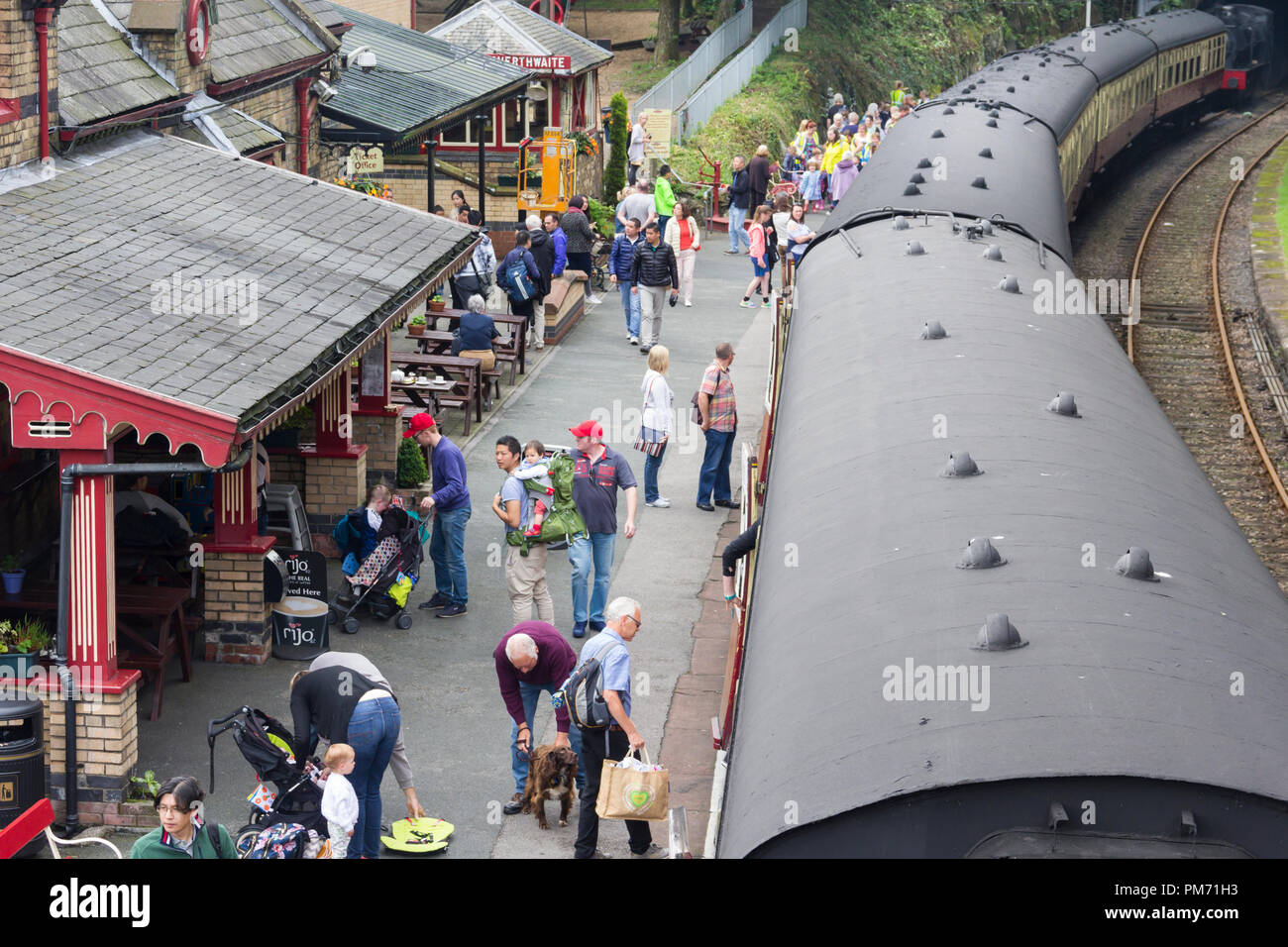 Busy train station platform at Haverthwaite preserved heritage railway in the Lake District as passengers disembark from the newly arrived train. Stock Photo