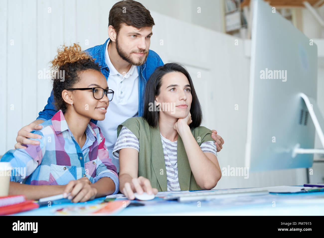 Portrait of three creative designers using computer while collaborating on project working at desk in office, copy space Stock Photo