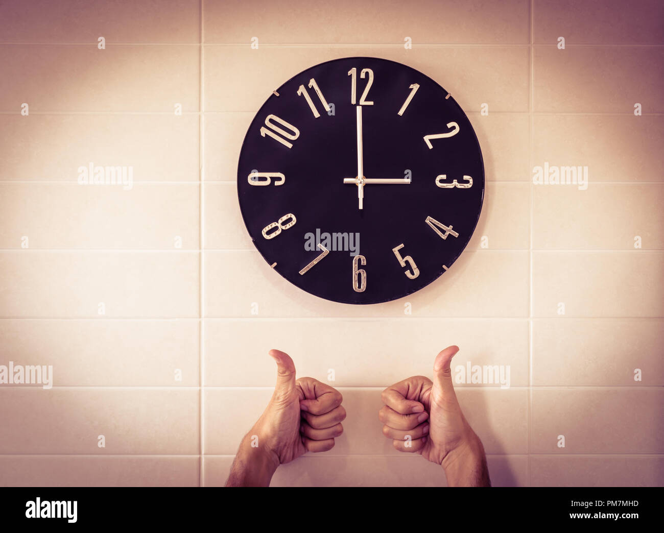 Big black clock on white wall. Time change. DST. Survey of the European Union on time change. Gesture of agreement. Thumbs up of Caucasian man. Stock Photo