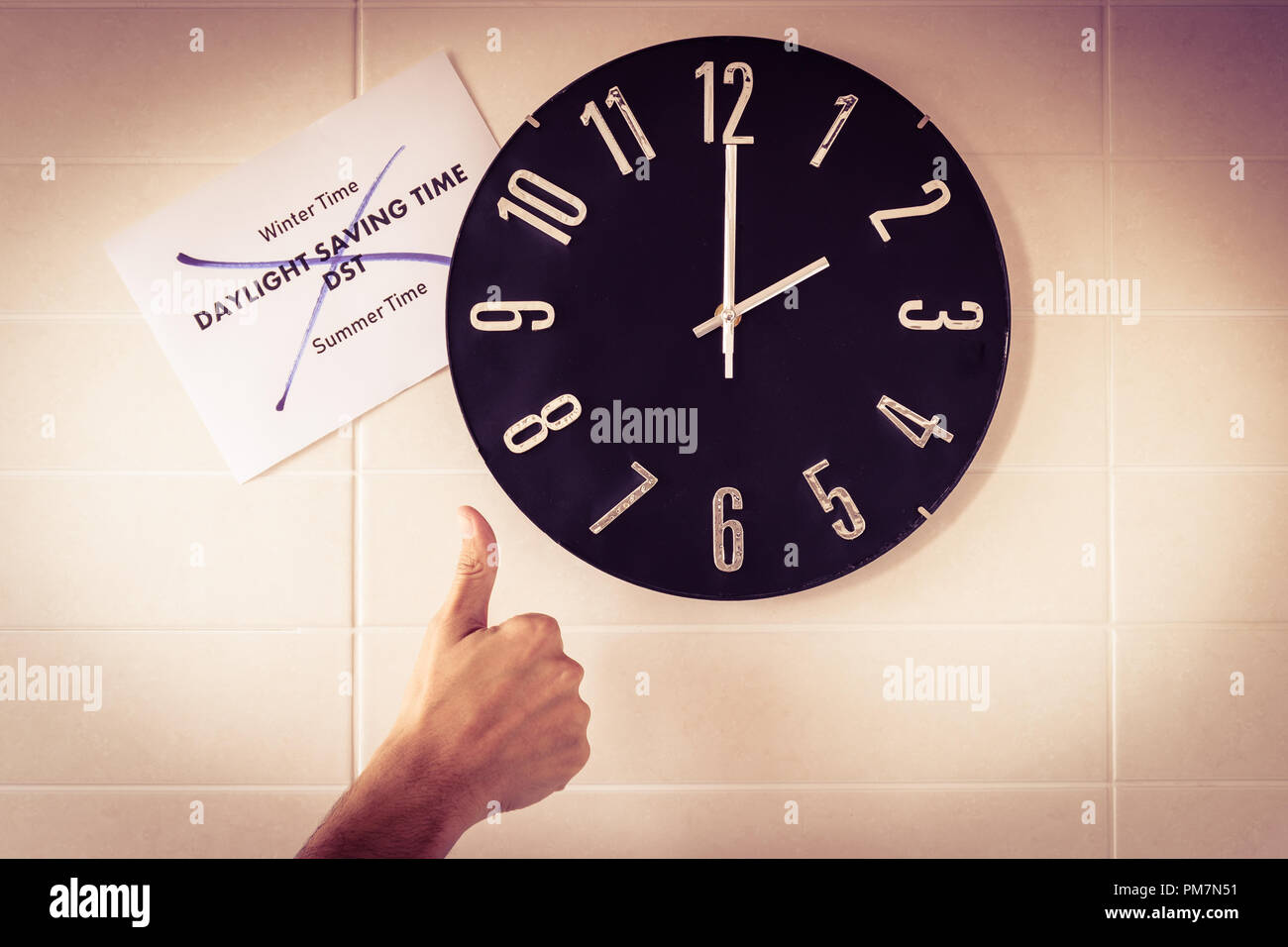 Big black clock on white wall. Time change. DST. Survey of the European Union on time change. Gesture of agreement. Thumb up of Caucasian man. Banner. Stock Photo