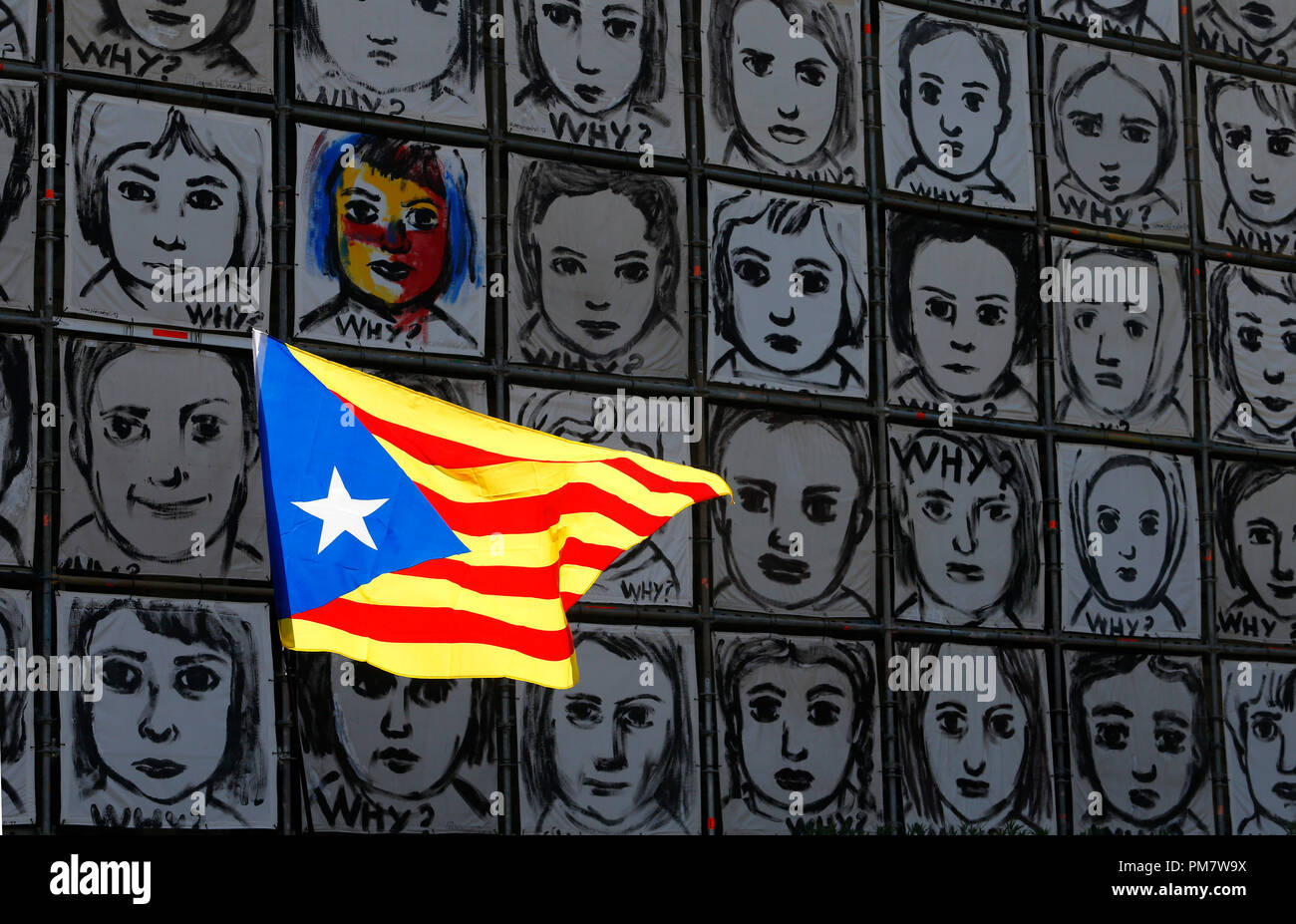 An Estelada, Catalan National flag,  waves next to a wall art by artist Carme Sole in Barcelona during their Diada, a yearly Catalan Nationalism day Stock Photo