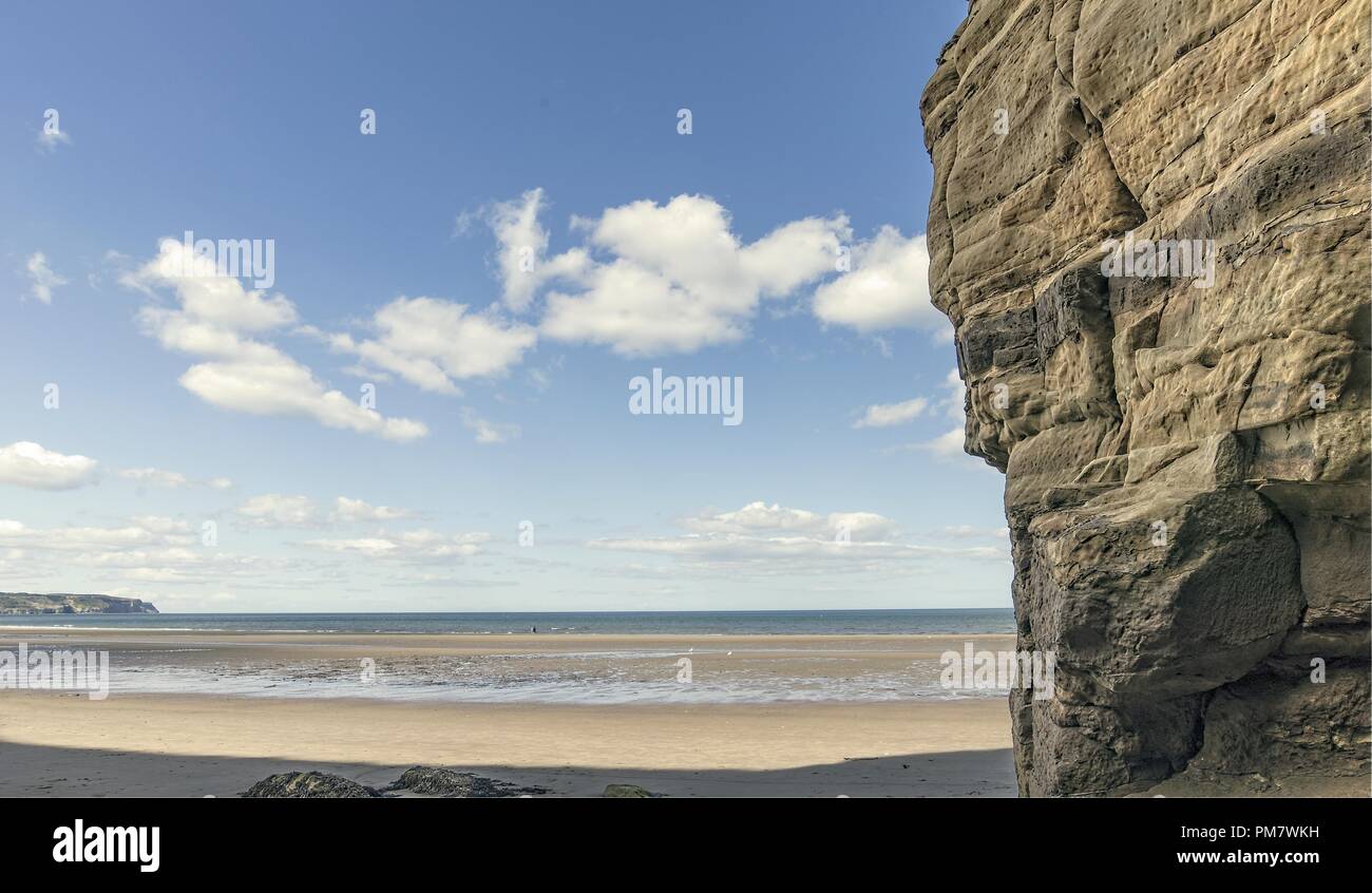 A wide stretch of water narrows as it runs to the sea across the beach