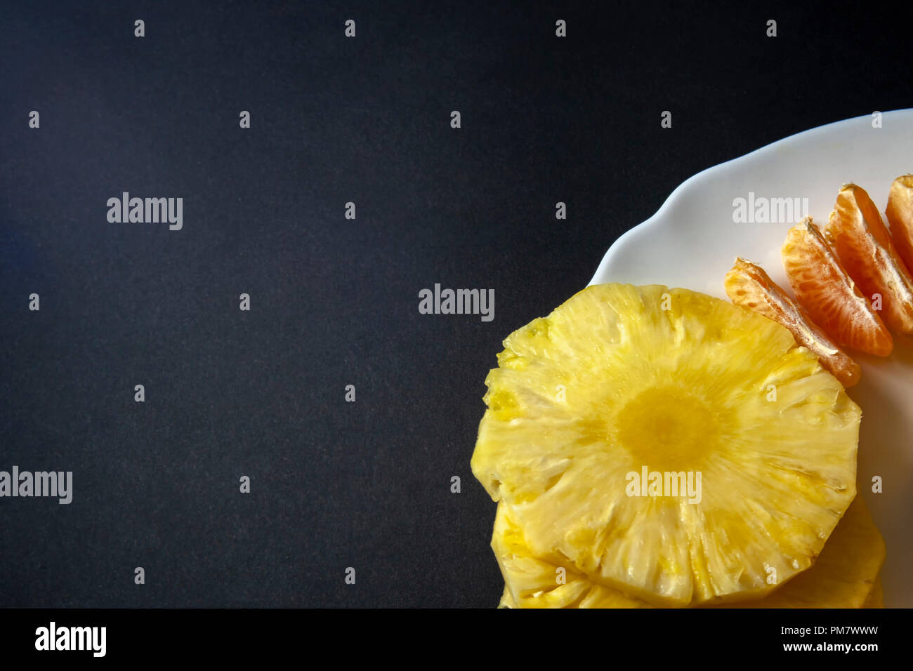 Mandarin orange and pineapple slices placed on white plate isolated on