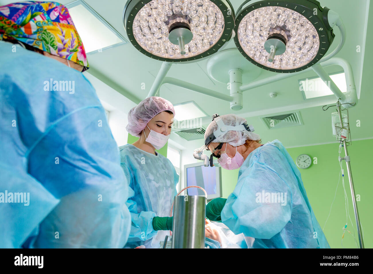Surgeon and his assistant performing cosmetic surgery on nose in