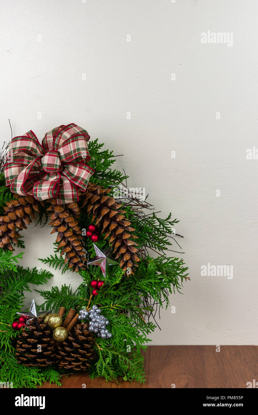 A Christmas wreath with cedar branches, pine cones, silver  stars, gold ornaments,  red berries, green and silver berry clusters with a red and green  Stock Photo