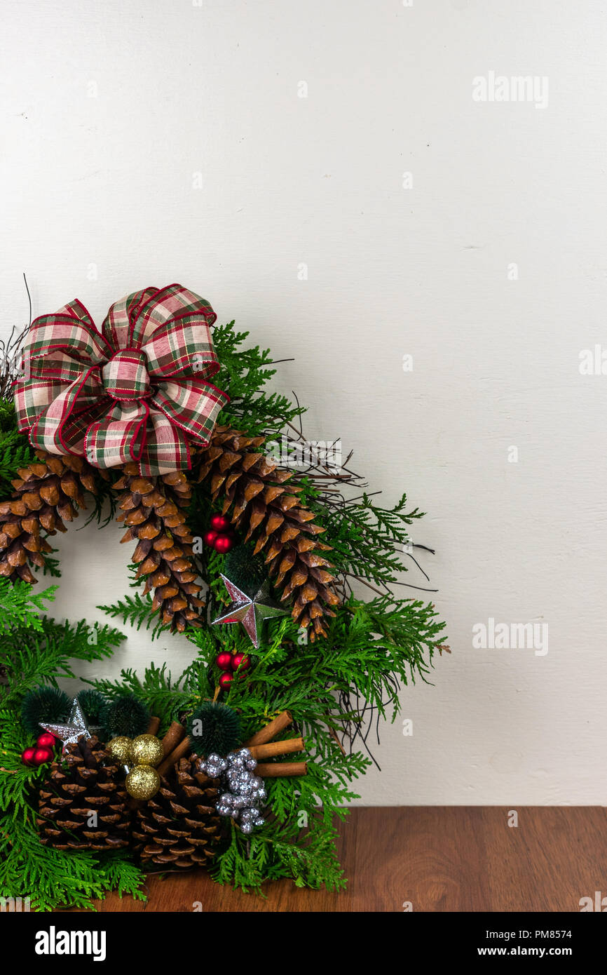A Christmas wreath with cedar branches, pine cones, silver  stars, gold ornaments,  red berries, green and silver berry clusters with a silver bow on  Stock Photo