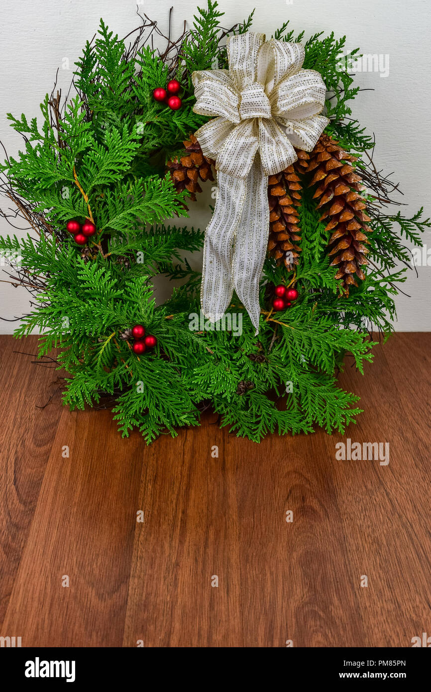 A Christmas wreath with cedar branches, pine cones and red berry ...