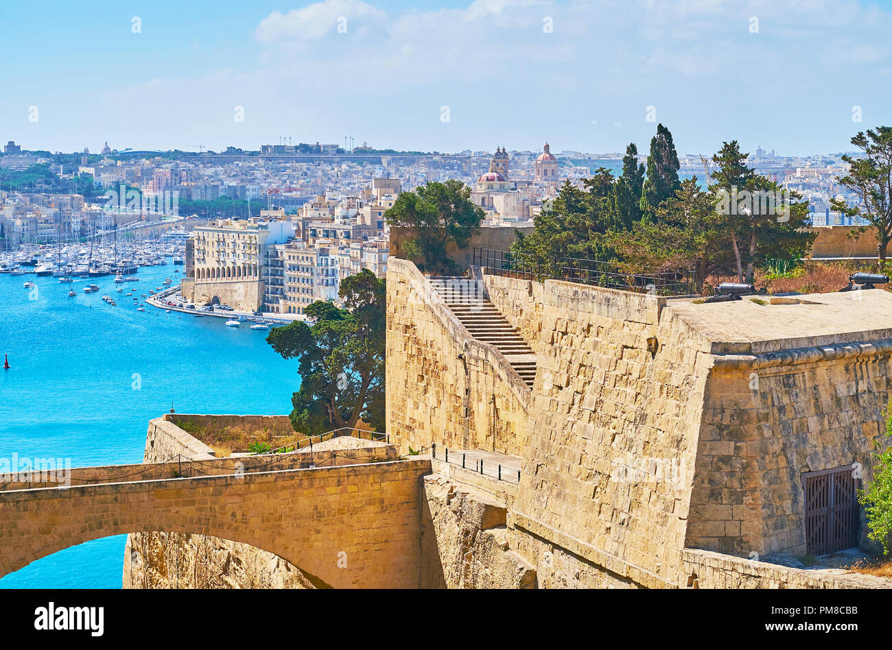The narrow bridge connects St Peter and Paul bastion with counterguard, the Grand Harbour of Valletaa and buildings of Senglea are seen on background, Stock Photo
