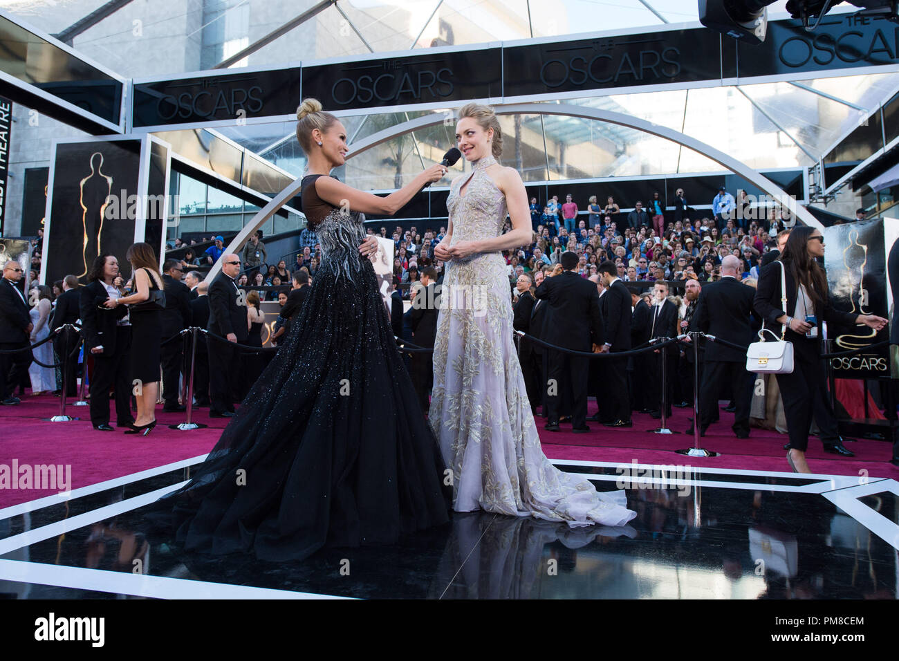 Actress Amanda Seyfried (R) talks with Kristin Chenoweth as she arrives for The Oscars® at the Dolby® Theatre in Hollywood, CA February 24, 2013. Stock Photo