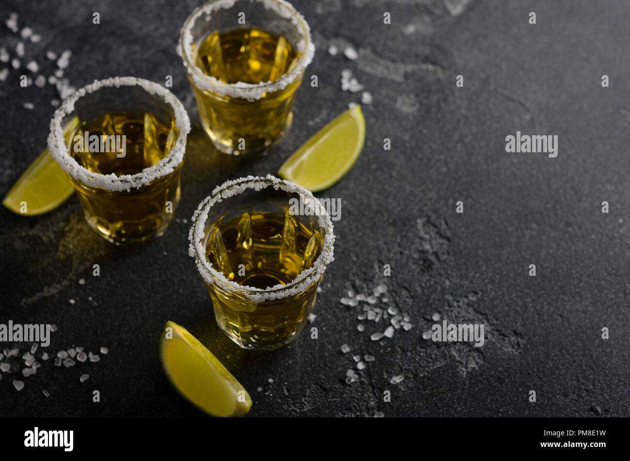 Gold tequila with lime and salt rim on dark stone or concrete background, selective focus. Stock Photo