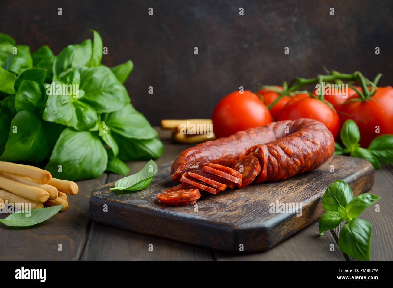 Chorizo sausage. Spanish traditional chorizo sausage with fresh herbs and tomatoes. Stock Photo