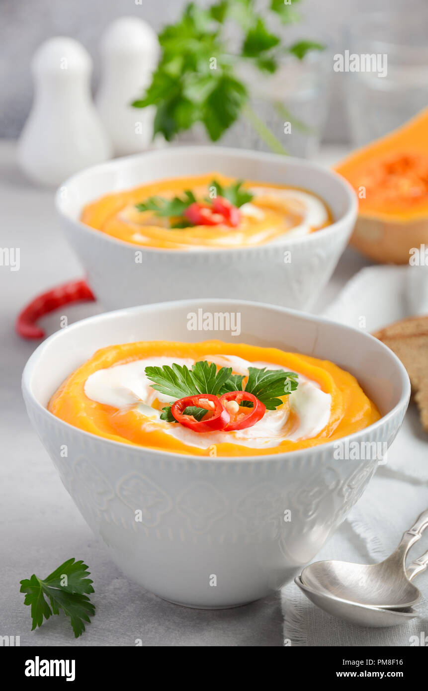 Pumpkin soup with cream and parsley on a gray concrete or stone background, selective focus. Stock Photo