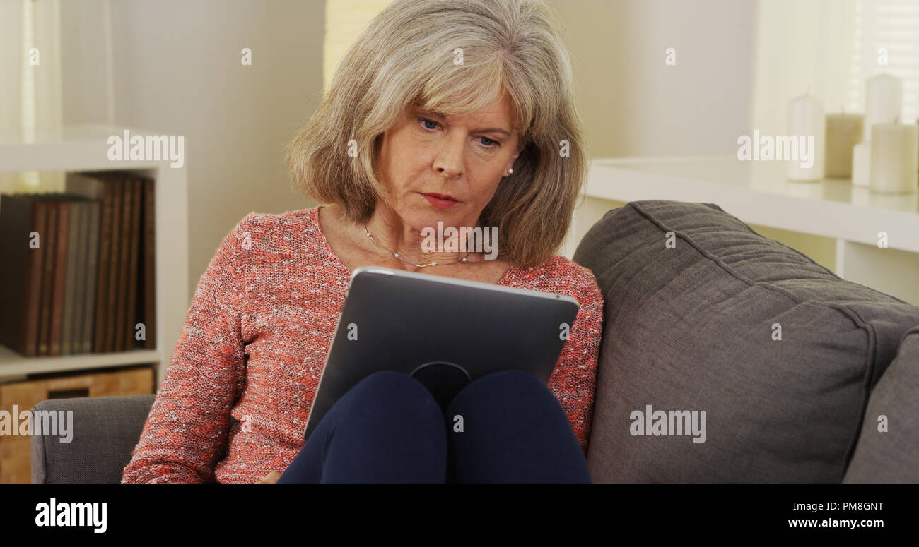 Beautiful mature woman tablet reading Stock Photo