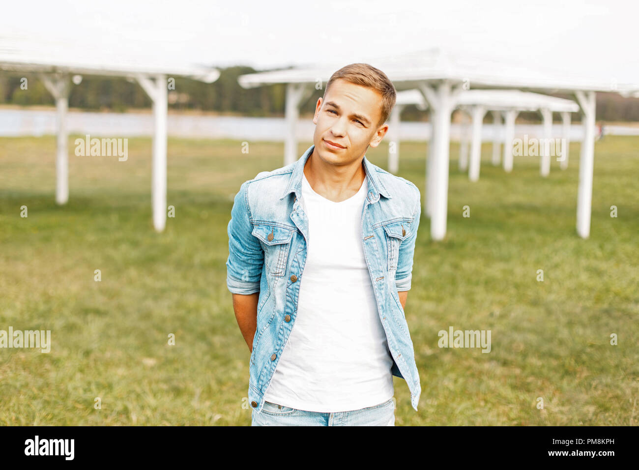 Young man in a denim jacket and white T-shirt posing on nature Stock Photo