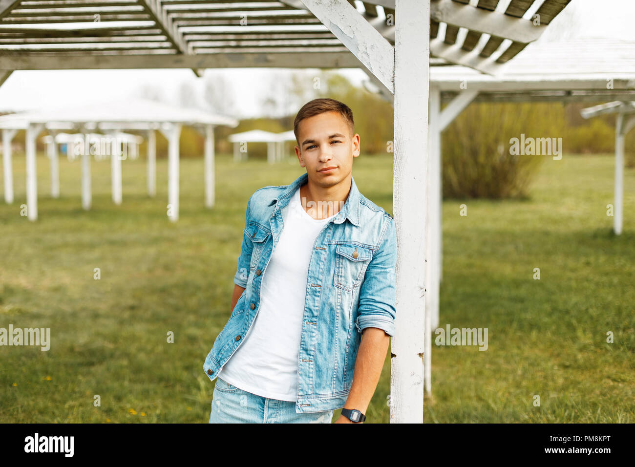 Handsome young man in a denim jacket and white shirt outdoors Stock Photo