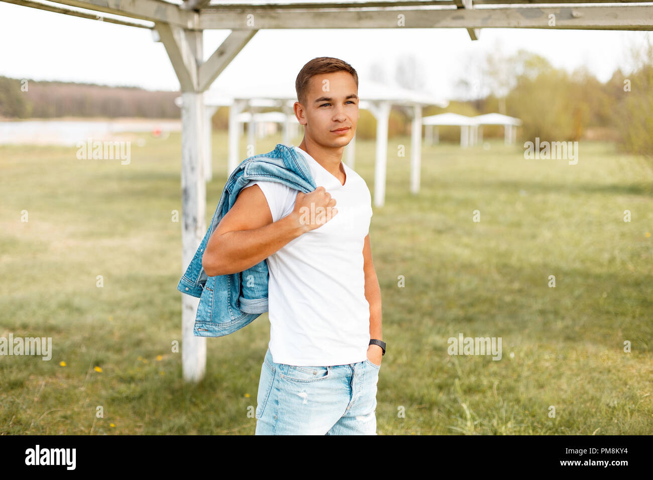 Handsome man in a white T-shirt with a jeans jacket outdoors Stock Photo