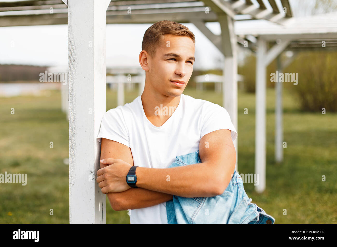 Handsome man in a white T-shirt with a clock on the nature Stock Photo