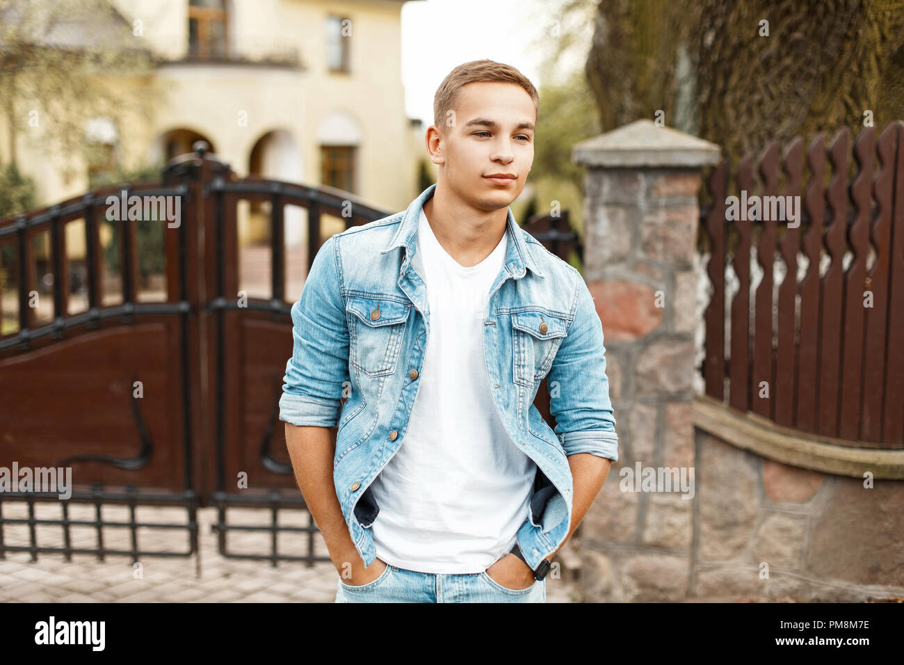 Stylish handsome young man in jeans clothes in a white shirt from a private house Stock Photo