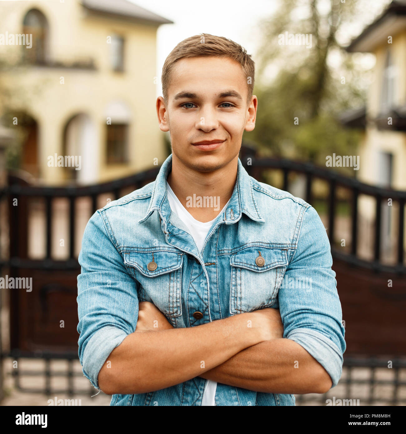 Portrait of a beautiful happy young man in a jeans jacket and a white T-shirt, outdoors Stock Photo