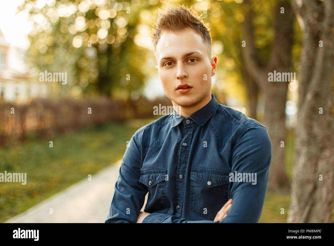 Portrait of a handsome young man in a stylish blue shirt in the park Stock Photo