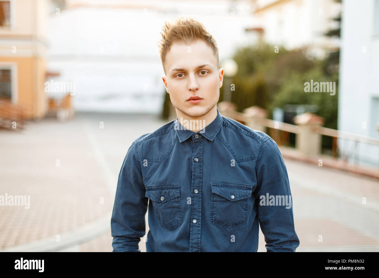Portrait of a young guy in a blue shirt outdoors on a sunny day Stock Photo