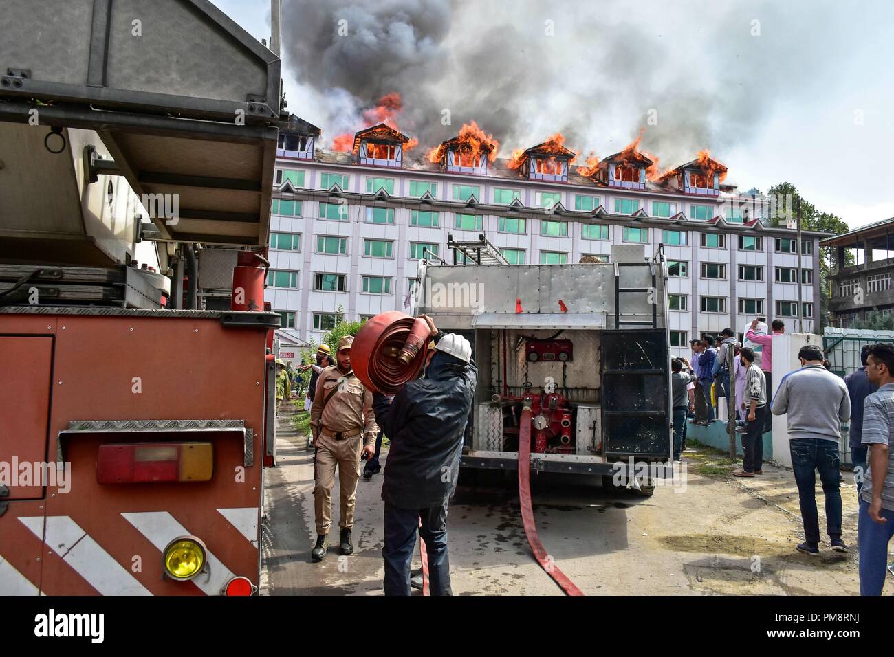 Firefighters seen at their trucks getting all equipment to extinguish the fire on the hotel building. A massive fire erupted at a local hotel here in Srinagar on Saturday, but there was no loss of life or injury according to police. Fire tenders were rushed to the spot and police, and fire and emergency services were trying to douse the flames. Stock Photo