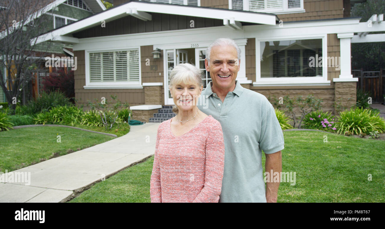 Senior couple standing smiling in front of new home Stock Photo - Alamy