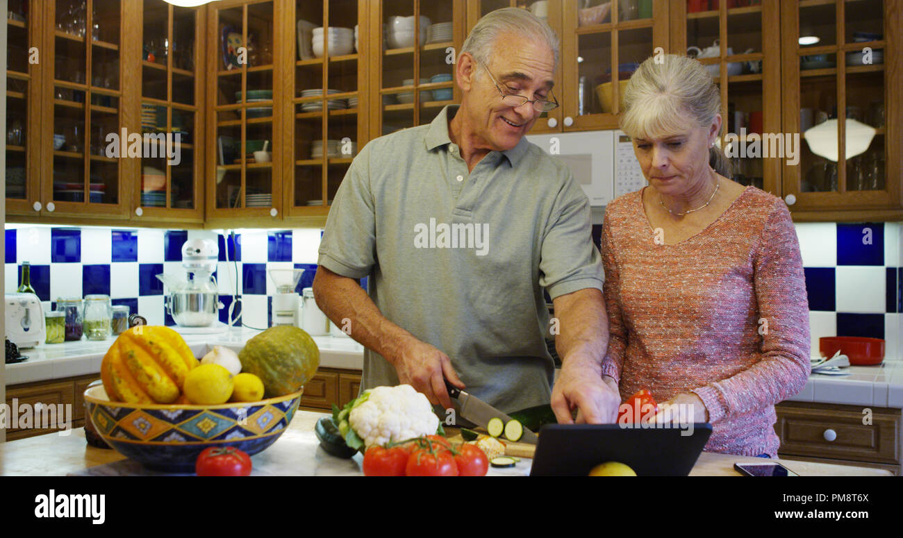 Senior couple using tablet computer in kitchen during lunch Stock Photo