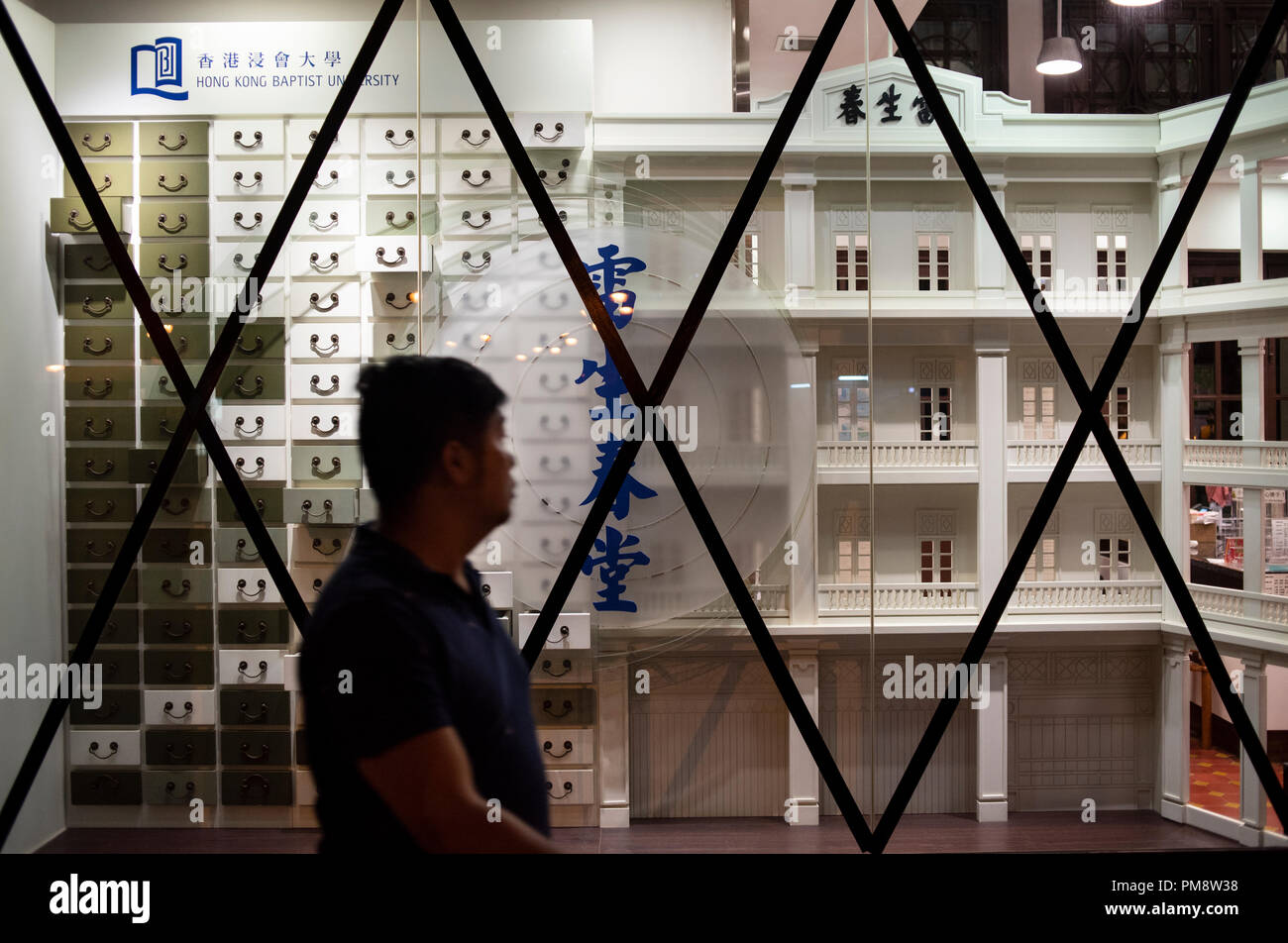 A pedestrian seen passing by Hong Kong Baptist University School of Chinese Medicine Lui Seng Chun with taped windows and doors. Windows and doors of buildings have been taped ahead of Super Typhoon Mangkhut arrival in Hong Kong, China. It is expected to land with a typhoon signal No. 8. Stock Photo