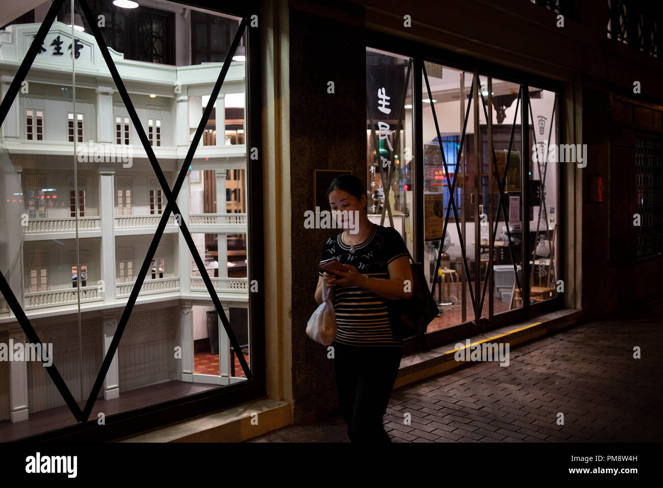 A pedestrian seen passing by Hong Kong Baptist University School of Chinese Medicine Lui Seng Chun with taped windows and doors. Windows and doors of buildings have been taped ahead of Super Typhoon Mangkhut arrival in Hong Kong, China. It is expected to land with a typhoon signal No. 8. Stock Photo