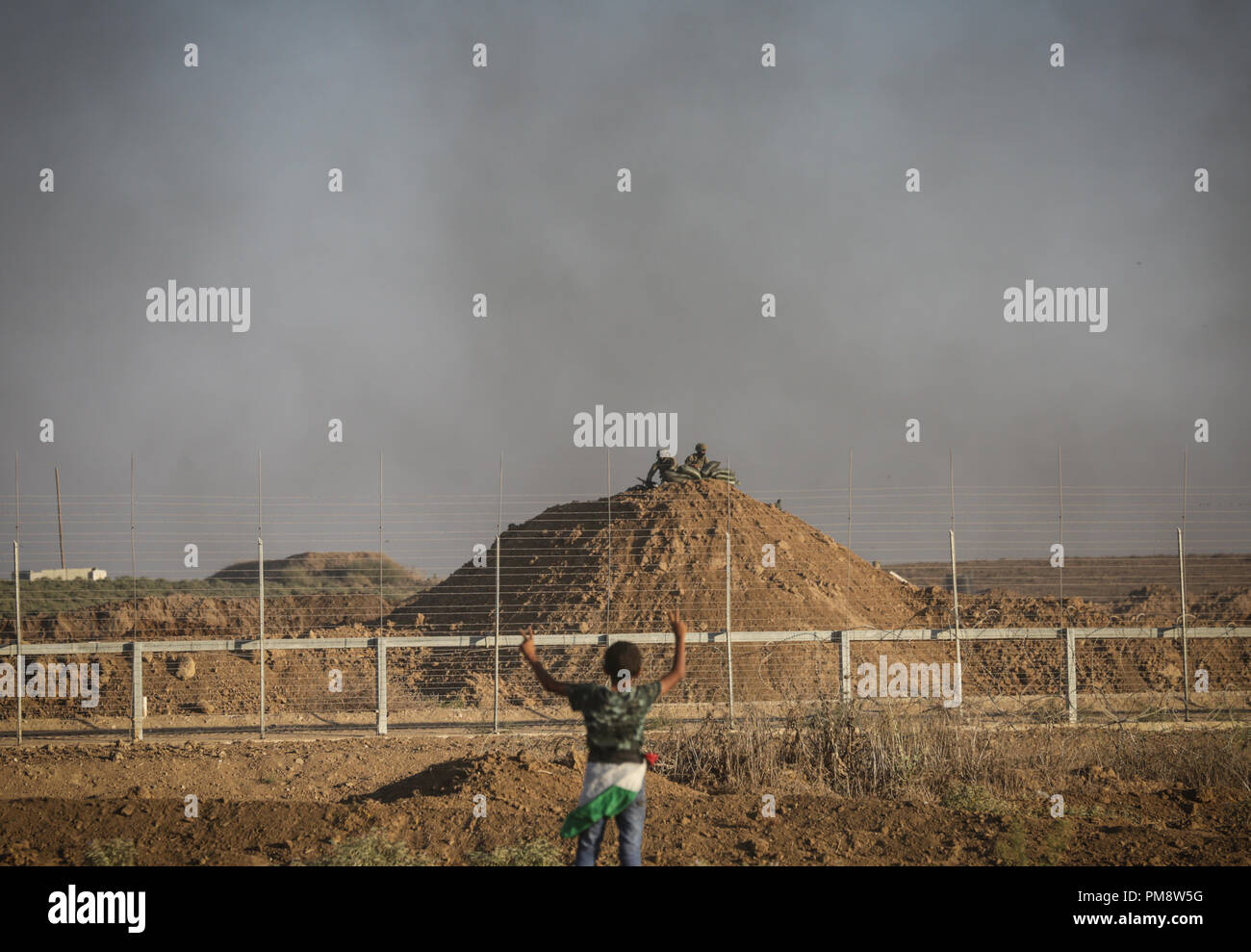 Palestinian protesters seen standing next to the Israeli fence during clashes. Clashes between Palestinian protesters and the Israeli forces during a protest along the Israeli fence East of Gaza City. Stock Photo