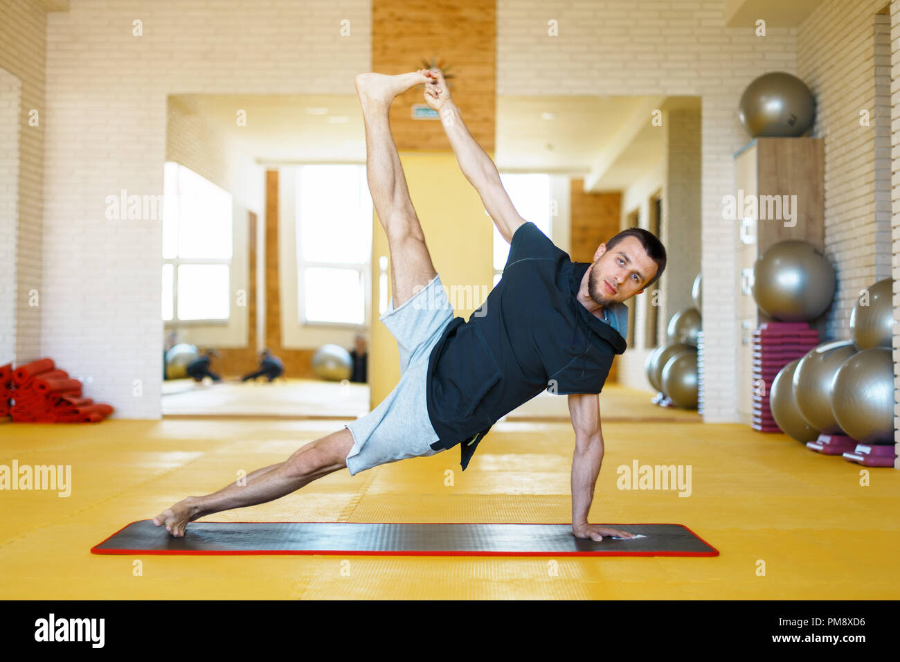 Young man practicing yoga in the gym Stock Photo