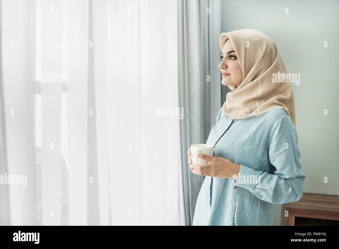 beautiful young woman wearing hijab drinking a cup of tea while Stock ...