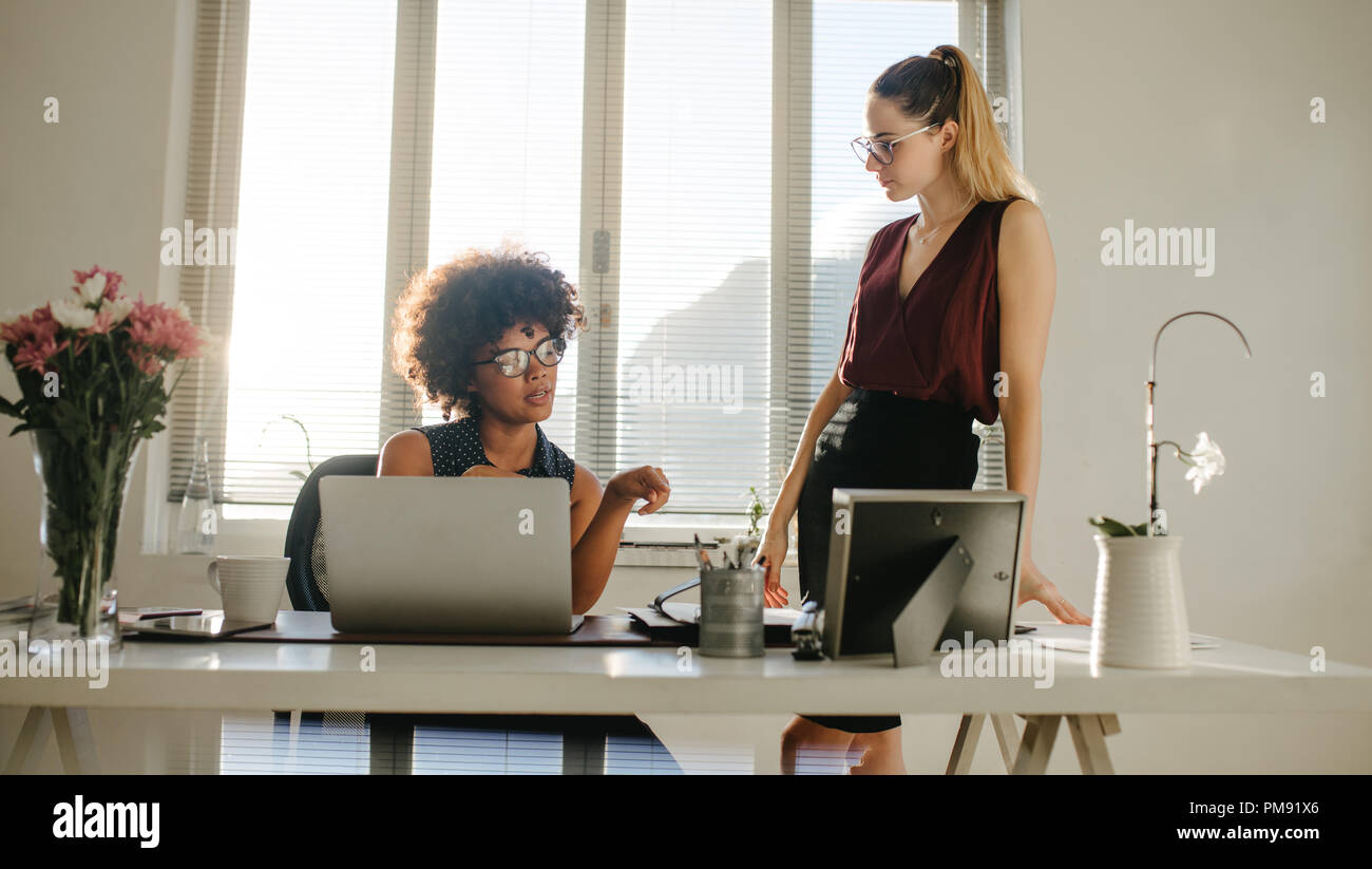 Portrait of two businesswomen discussing work in office. Young women talking about new project in modern office. Stock Photo