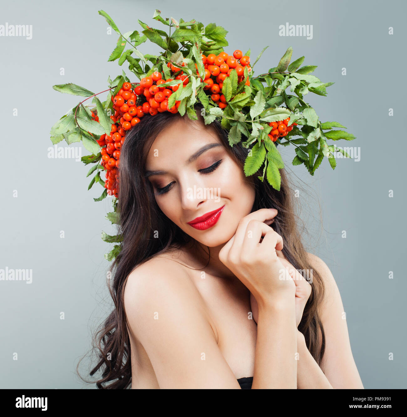 Young woman with red lips makeup, long permed hair and rowan berries and leaves wreath on head Stock Photo