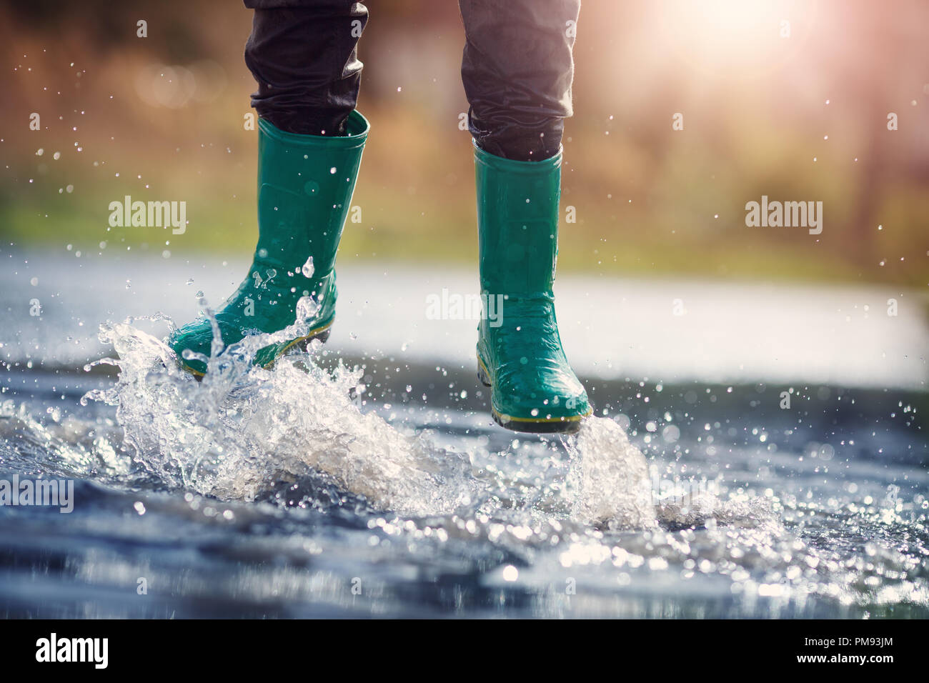 Child walking in wellies in puddle on rainy weather Stock Photo