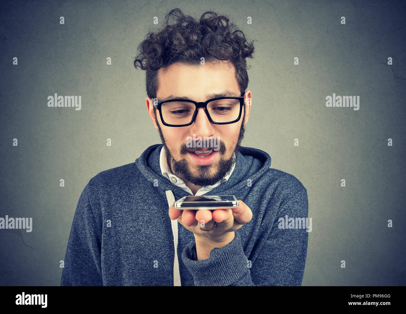 Hipster man using a smart phone voice recognition function isolated on wall background Stock Photo