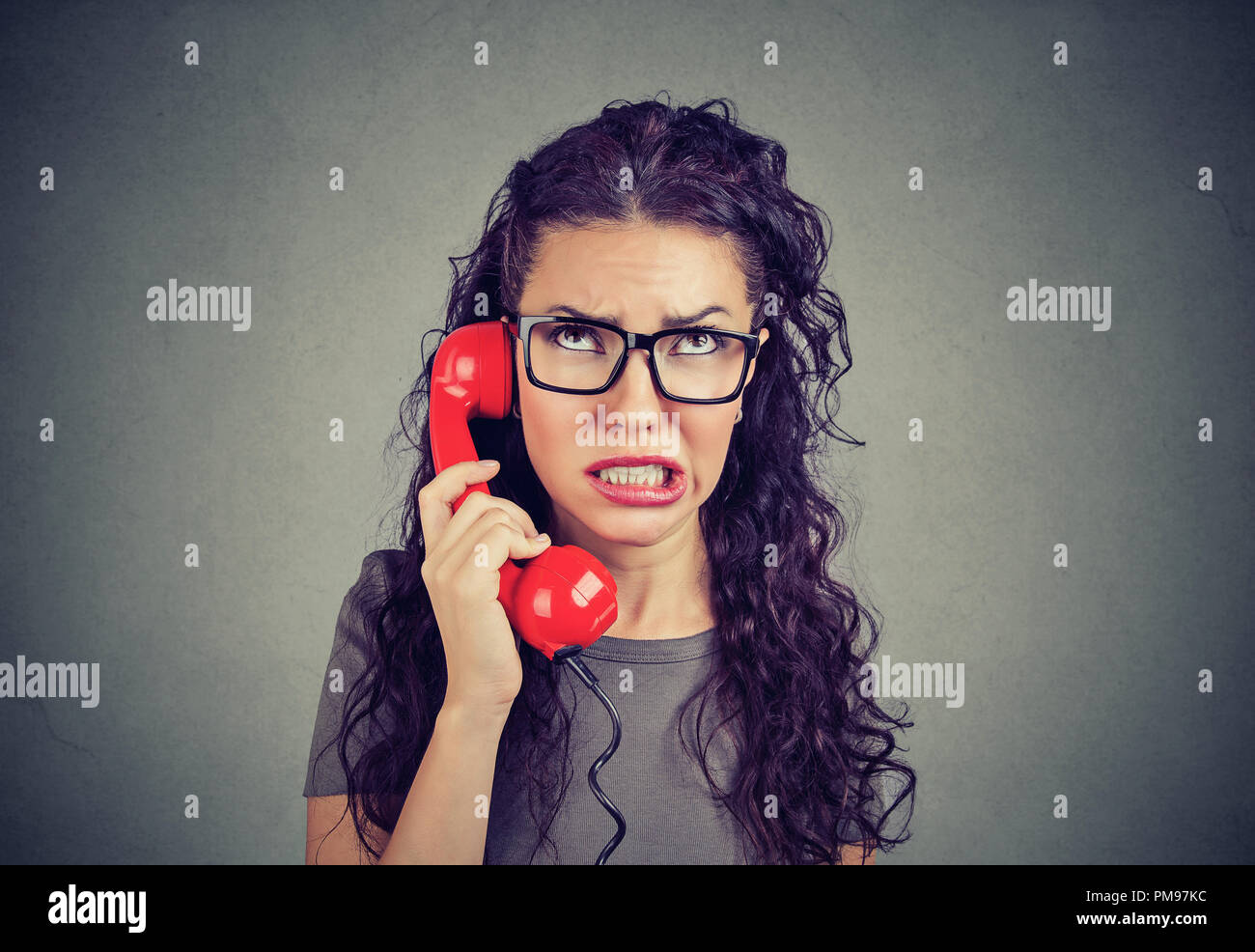 Young displeased upset woman speaking on a telephone and looking disgusted with bad news and problems Stock Photo