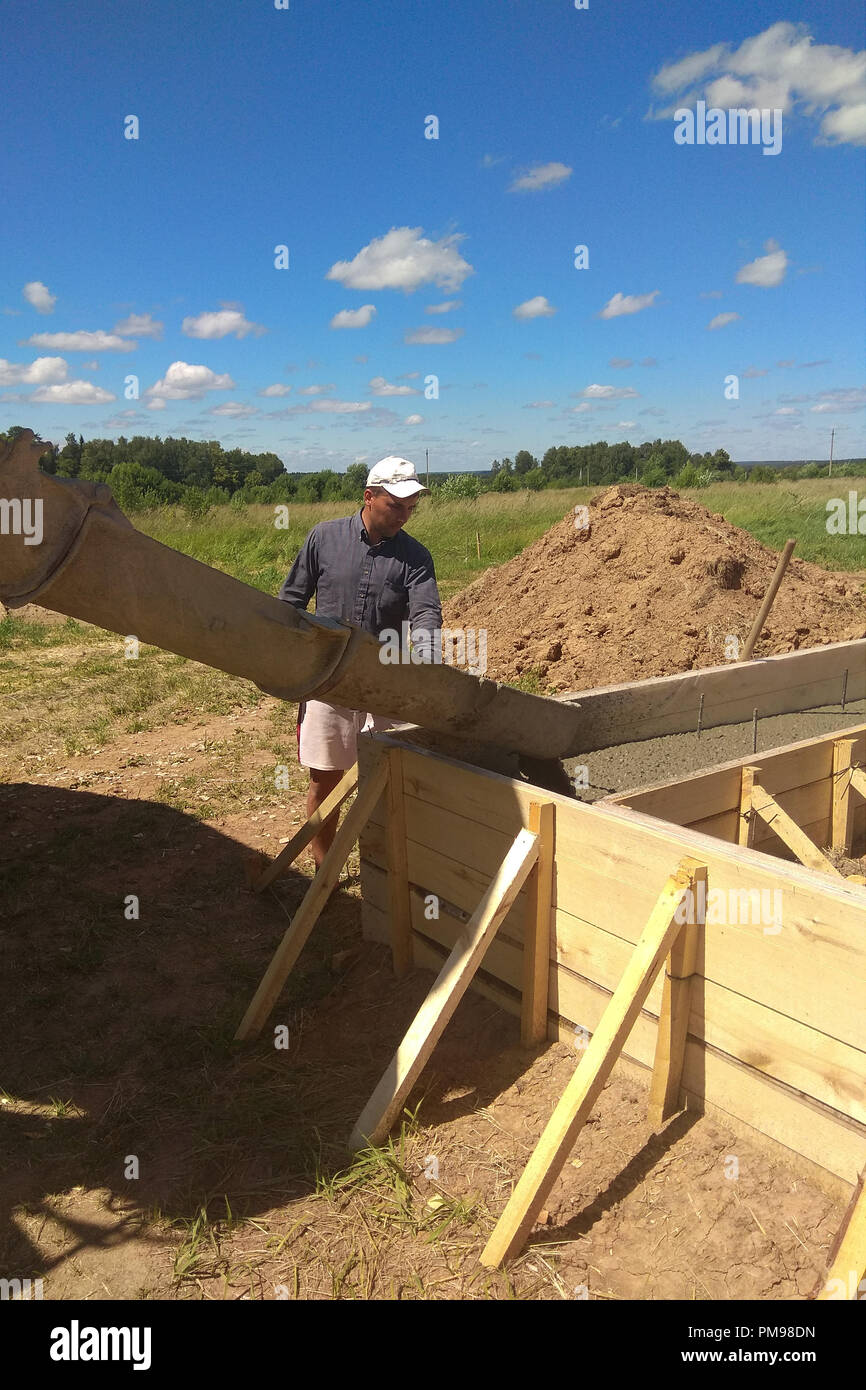 building construction worker pouring cement or concrete with pump tube