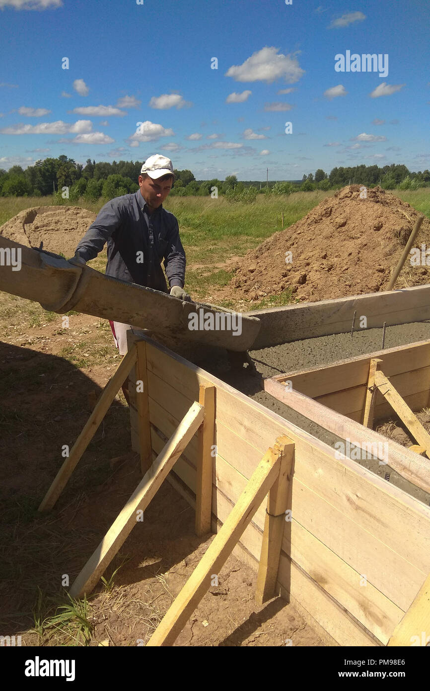 building construction worker pouring cement or concrete with pump tube