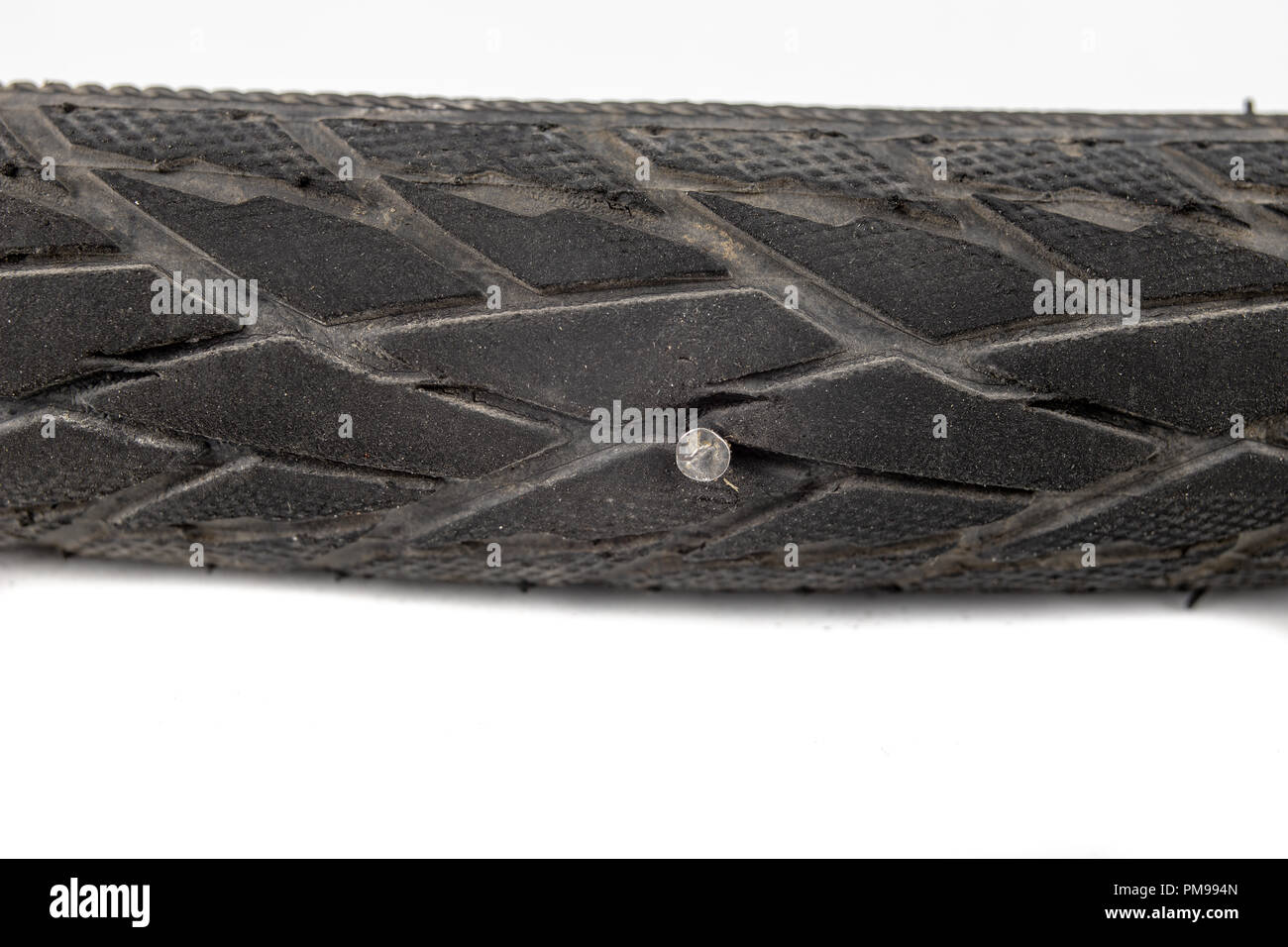 A beaten bicycle tire in the workshop. A bicycle wheel pierced with a nail. Light background. Stock Photo