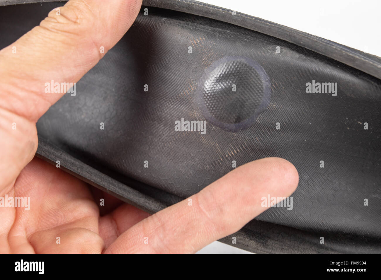 A beaten bicycle tire in the workshop. A bicycle wheel pierced with a nail. Light background. Stock Photo