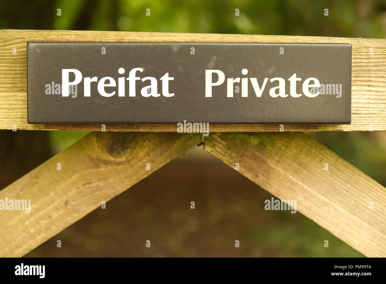 Welsh language Preifat Private sign on wooden gate fence with greenery