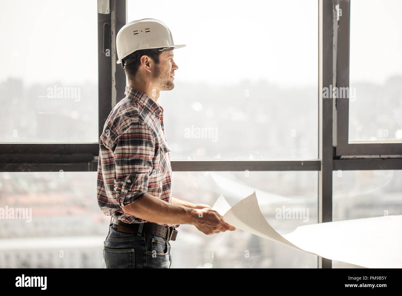 handsome builder is looking away and slitting his eyes Stock Photo