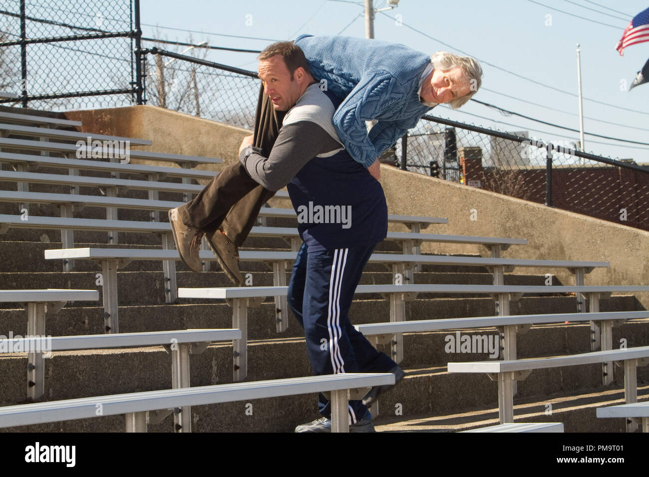 Scott Voss (Kevin James) carries Marty (Henry Winkler) over his shoulder as added weight while he works out climbing the bleacher stairs in Columbia Pictures' HERE COMES THE BOOM. Stock Photo