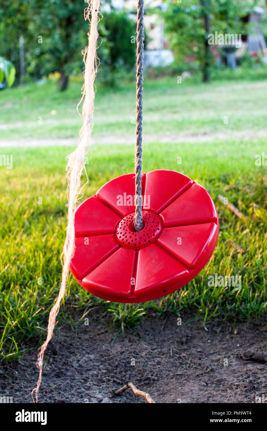 Picture of a red, round swing for kids in the backyard Stock Photo