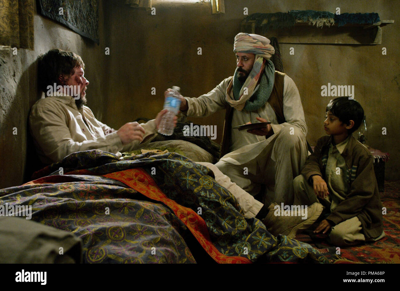 (L to R) Marcus Luttrell (MARK WAHLBERG) is treated by Gulab (ALI SULIMAN) and his young son (ROHAN CHAND) in 'Lone Survivor' Stock Photo