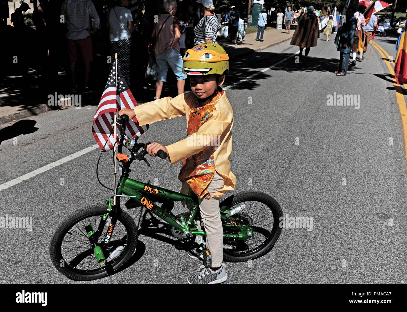 Vietnamese-American boy on his two-wheel bicycle with an American flag on its handlebars takes part in the 73rd One World Day celebration in Cleveland Stock Photo