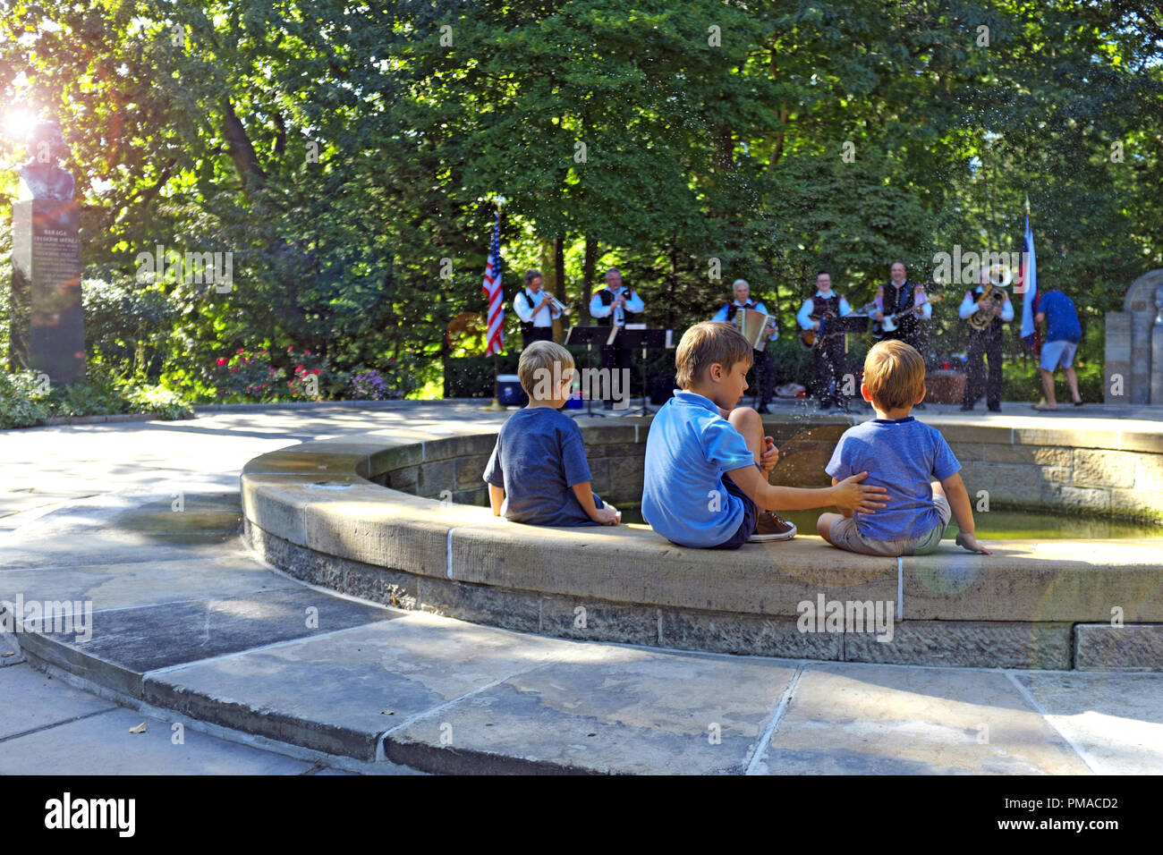 Three young boys sit cooling off in the Cleveland Cultural Gardens as they listen to a Slovenian band during the 73rd Annual One World Day celebration Stock Photo