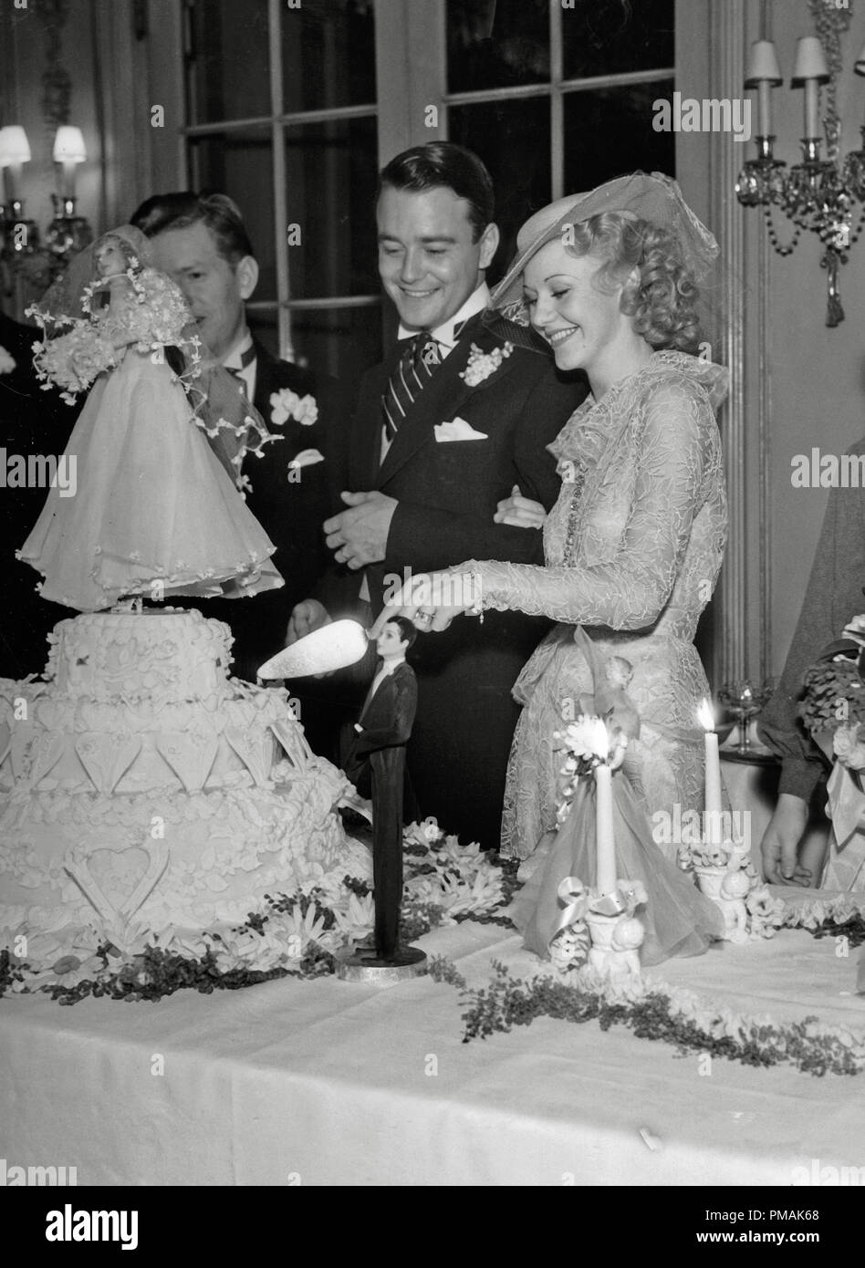 Ginger Rogers and Lew Ayres cutting their cake on their wedding day at